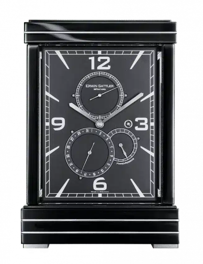 ERWIN SATTLER METRICA II.
Leverbaar in zwart gelakt of in Notenhout beide hoogglans gepolijst met metaal inleg, 27,5 cm hoog, 18,50 cm breed en 12 cm diep. Ontspiegeld mineraal glas. Uurwerk Sattler Kaliber 1385. Loopduur 15 dagen. Veer opwinding voorzien van een via een Schneck geregelde krachtsoverbrenging. Regelbaar Zwitsers Echappement. 12 Precisie kogellagers en 11 Robijn lagers. Wijzerplaat in zwart of zilver met datum aanduiding, gangreserve en seconde wijzer. Staal gepolijste wijzers bij de zwarte wijzerplaat of geblauwd stalen wijzers bij de zilveren wijzerplaat. 
